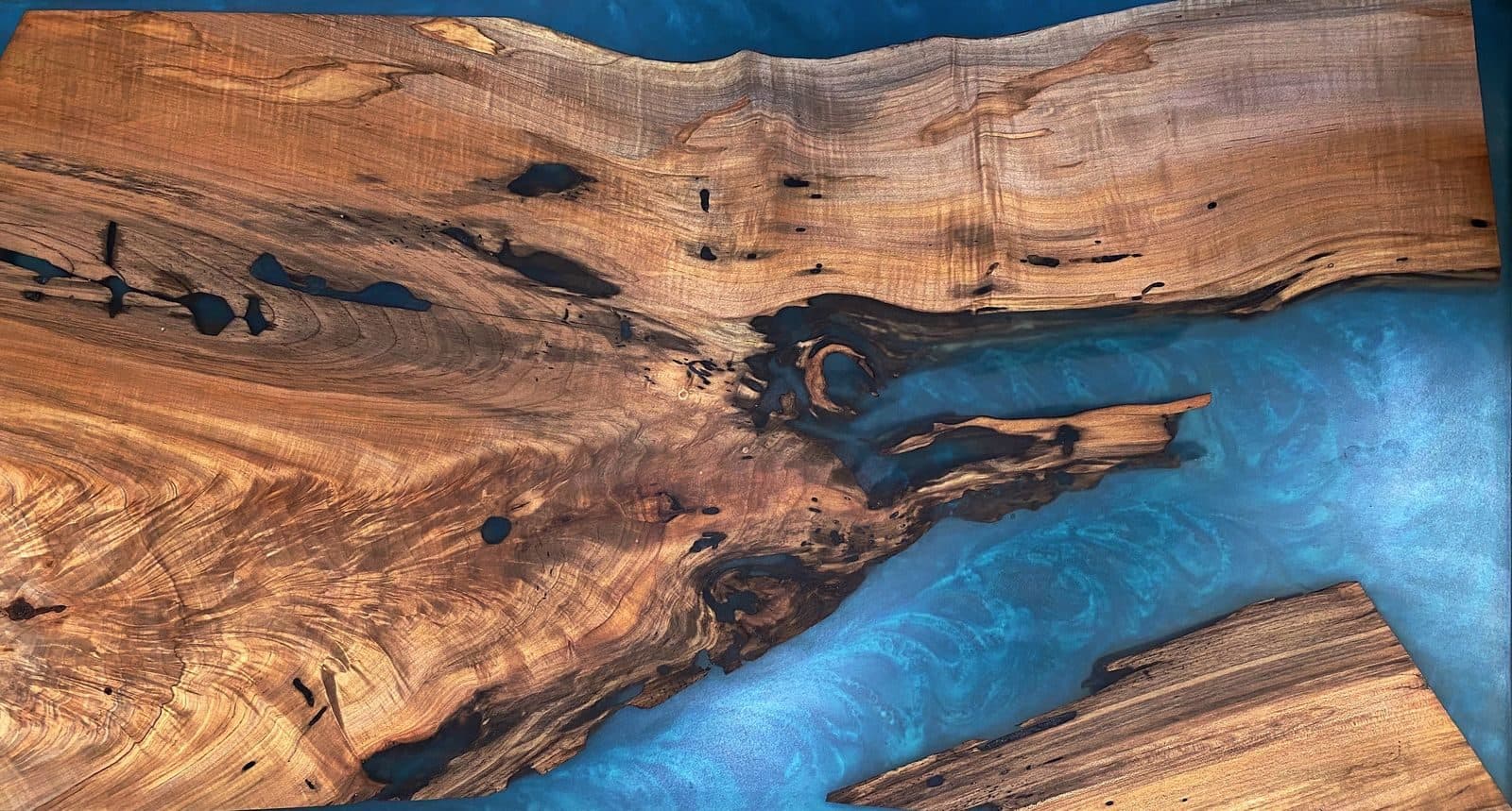 Top-down view of a live-edge walnut river table with blue epoxy