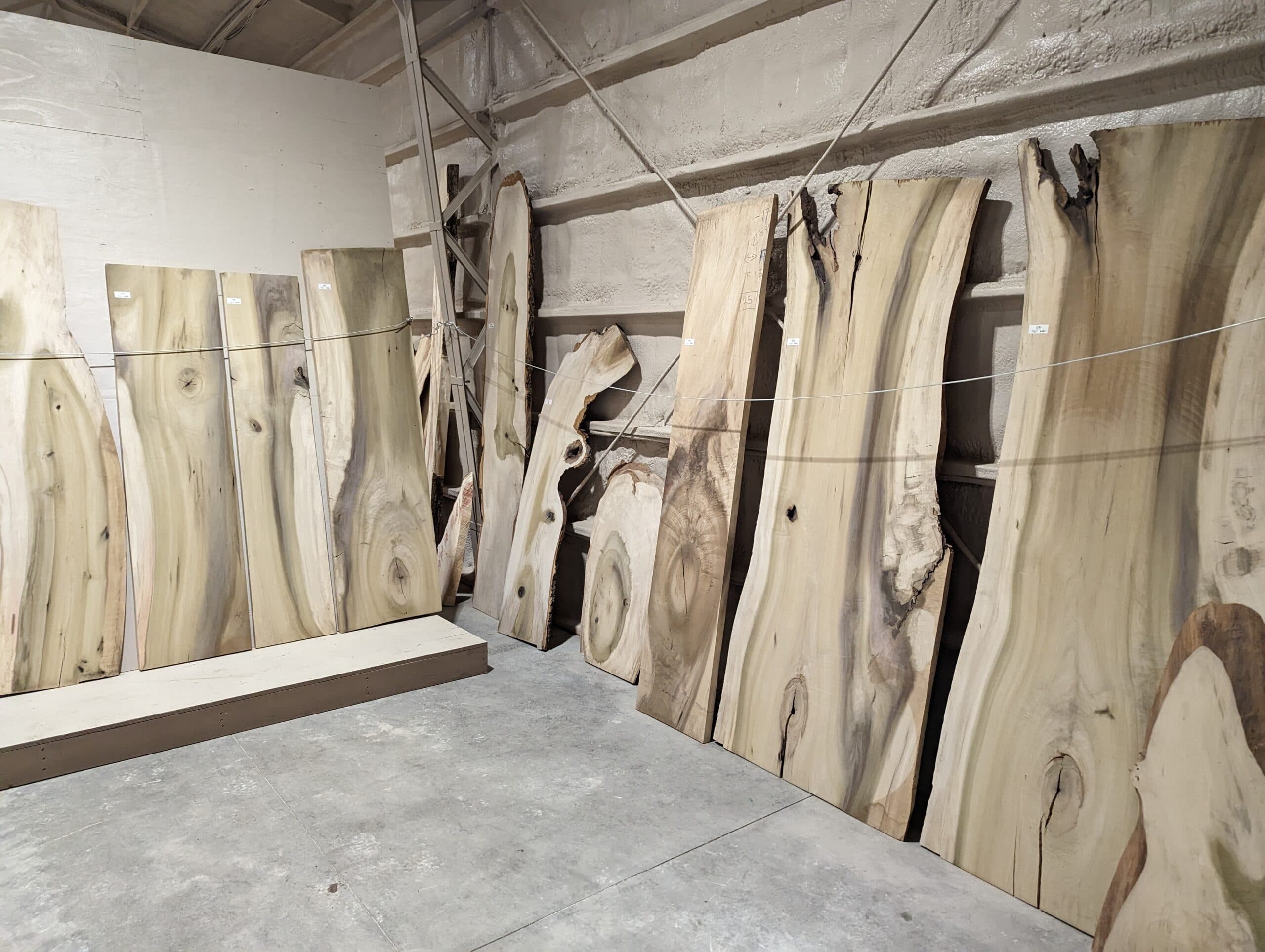 Live-edge hardwood slabs staged against warehouse wall